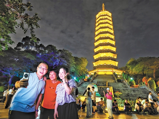成功登頂?shù)氖忻衲贸鍪謾C(jī)與龍光塔合影。