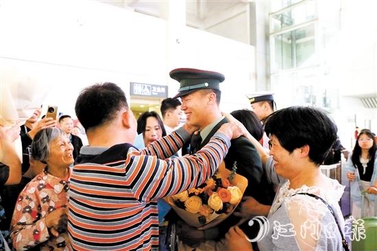身著軍裝的返鄉(xiāng)退役士兵逐一出站，迎接他們的是鮮花與擁抱。
