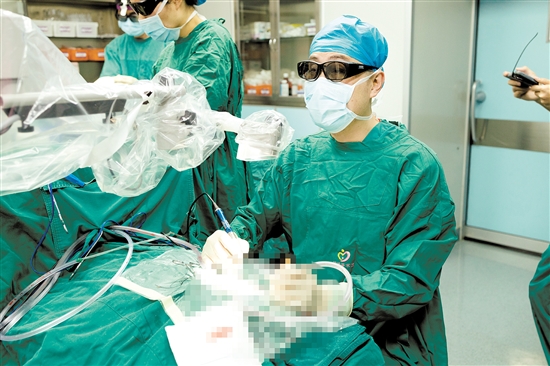 術中，醫(yī)生查看顯示屏，為患者植入人工耳蝸。