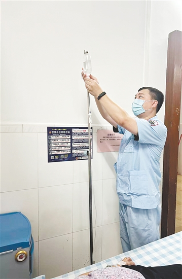 吳益浩核對藥液、為患者調(diào)整輸液流速。