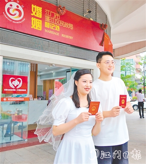 一對(duì)新人在蓬江區(qū)民政局婚姻登記處門口合影留念。