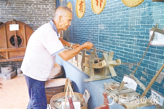 新華村打造農耕文化展館，留住鄉(xiāng)村記憶。圖為村中老人向記者介紹農具。