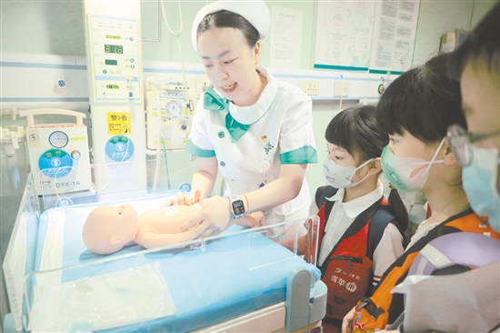 醫(yī)護人員為小記者演示新生兒輻射保暖臺的用途。