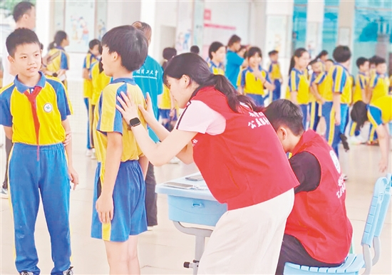 華南理工大學體育學院運動與健康科研團隊為學生進行專業(yè)的脊柱側(cè)彎篩查。