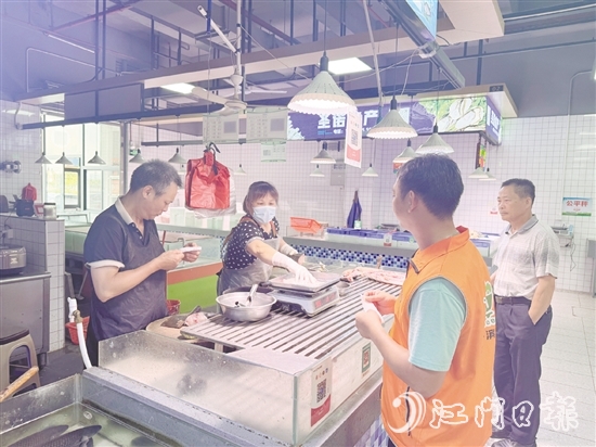 買菜易的平臺接單員李叔（橙色馬甲）正在魚攤旁等待取單。