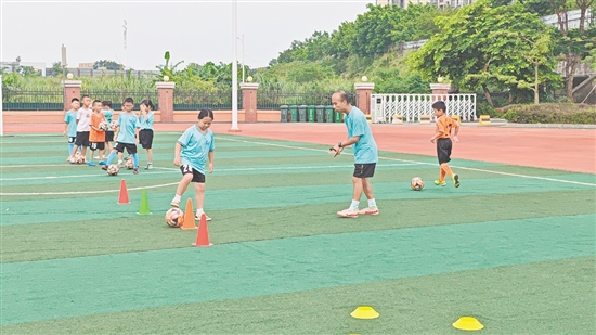 學(xué)生在教練的指導(dǎo)下學(xué)習(xí)足球技巧。