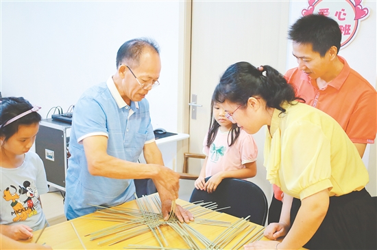 孩子和家長(zhǎng)在手藝人的指導(dǎo)下學(xué)習(xí)編織小竹筐。