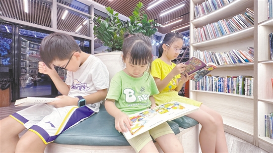 低年級(jí)學(xué)生圍坐在書(shū)架旁閱讀繪本。