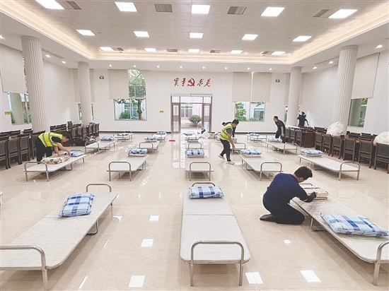 工作人員正在臨時(shí)庇護(hù)場所鋪設(shè)床位。