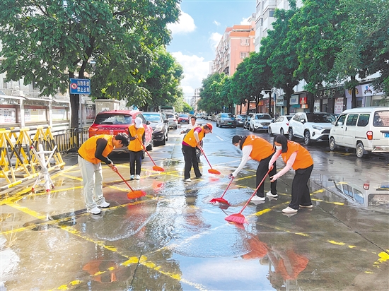 廣東江門中醫(yī)藥職業(yè)學(xué)院大學(xué)生志愿者合力清掃街道積水。