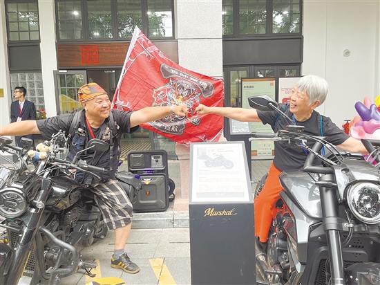 珍姨（右）坐在機車上與其他人碰拳互動。