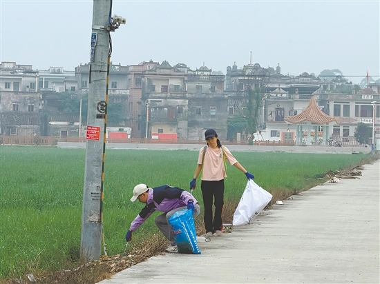 新村民走在鄉(xiāng)村道路清理垃圾。