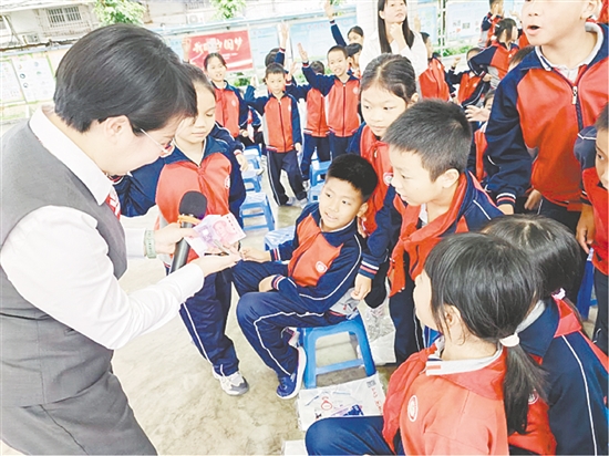 宣講員以第五套人民幣為教具，讓孩子們學(xué)會(huì)識(shí)假技巧。