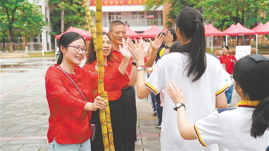 老師們手持甘蔗和學(xué)生們擊掌，寓意考試“掂過碌蔗”。